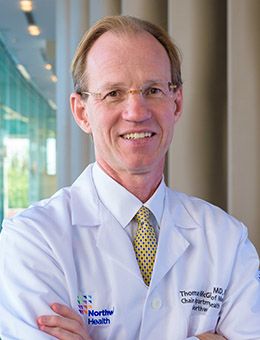 Thomas McGinn, MD, wearing a physician coat and gold tie